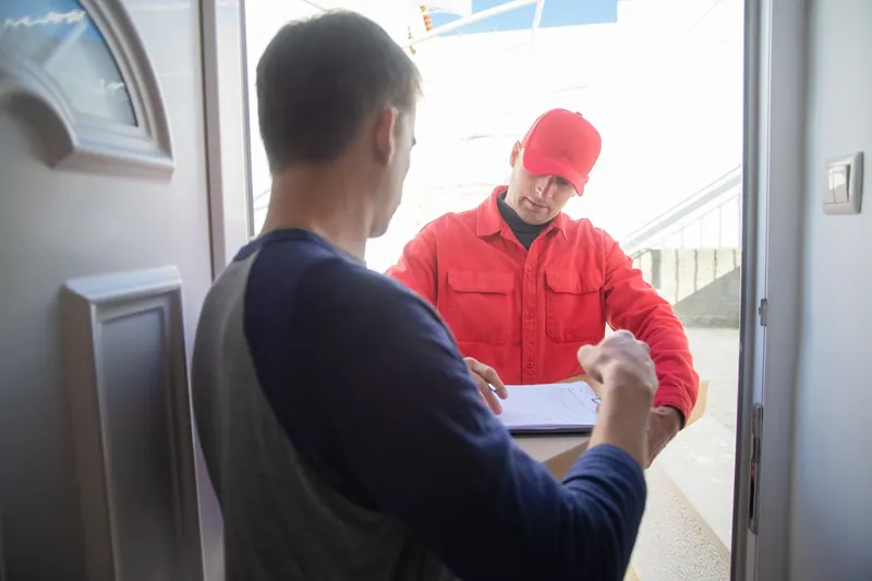 Persona revisando el correo junto a la puerta de casa